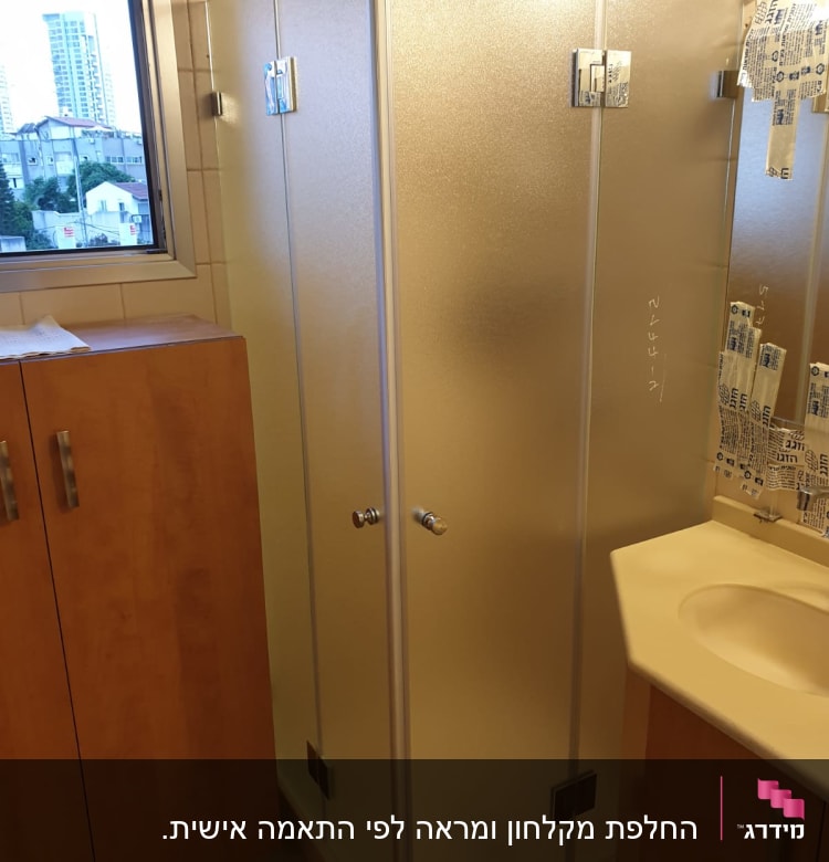 מקלחון זכוכית עם דלתות מתכת בחדר אמבטיה